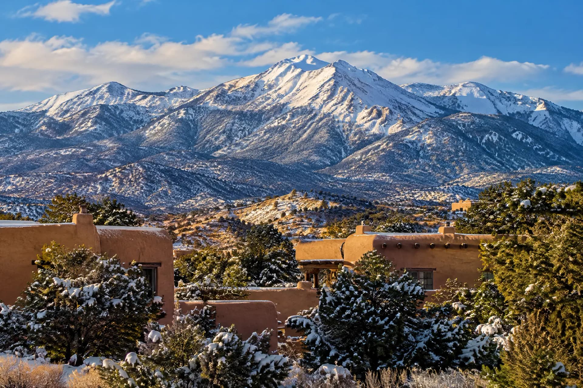 Snow-capped high desert mountains above adobe homes